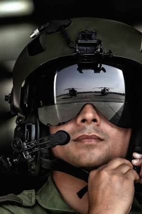 An aviator wearing a flight helmet and visor, adjusting the helmet strap