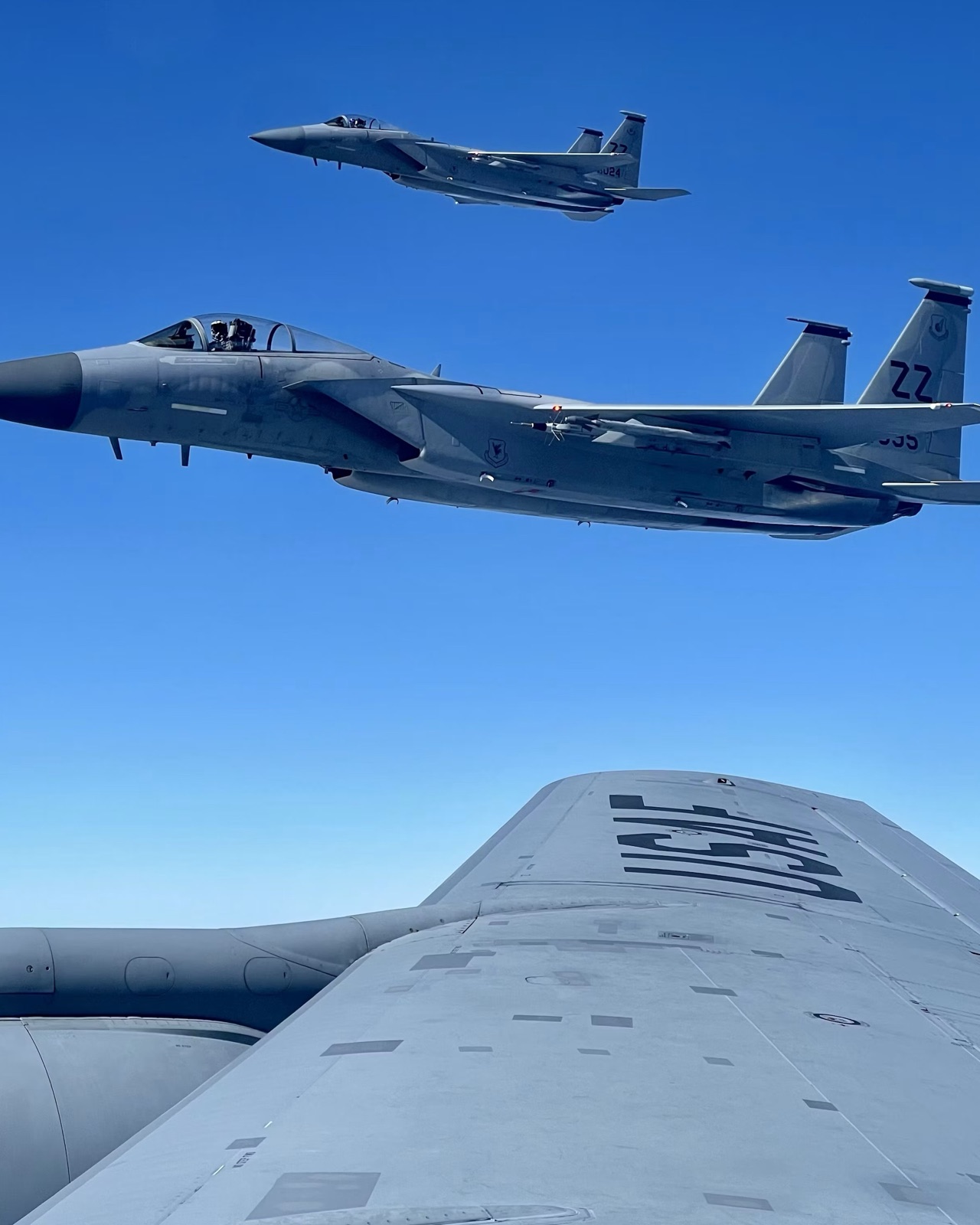 A fighter aircraft seen close alongside, showing airframe panels, control surfaces and external stores